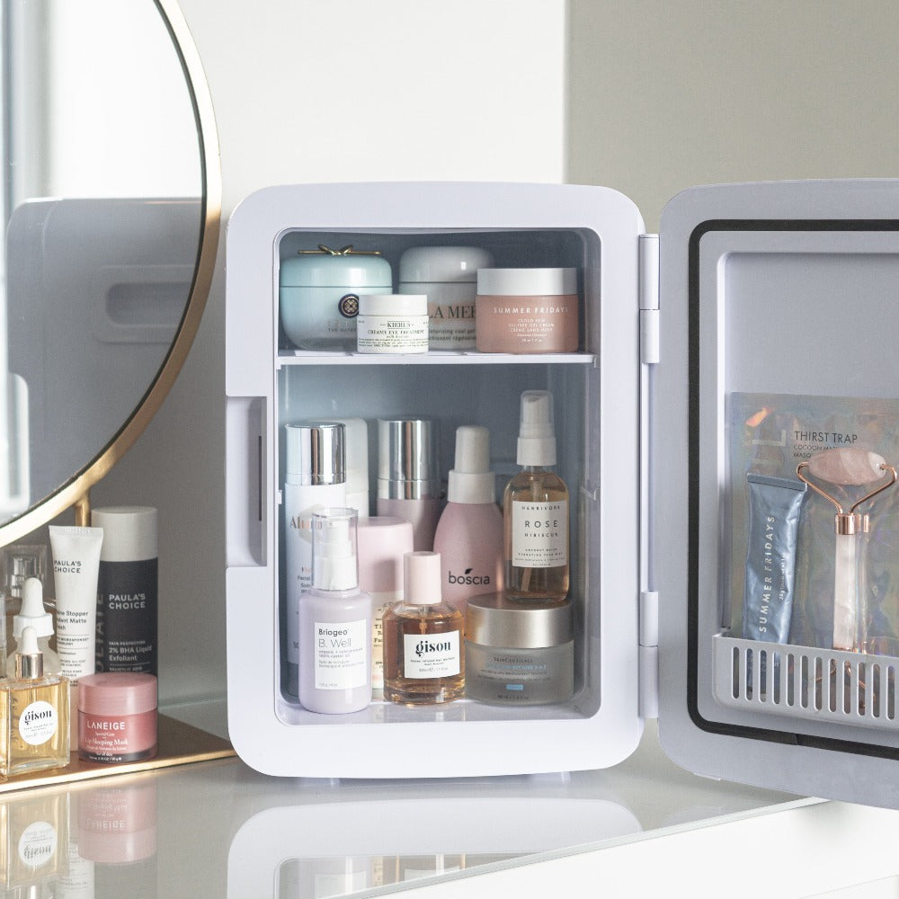 The Jumbo Marble Cosmetics Fridge with the door open showing skincare products, sheet masks, and facial roller on vanity table